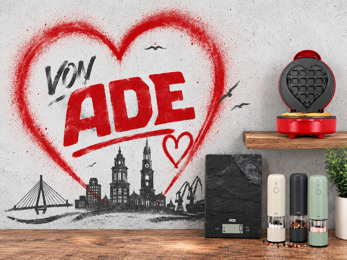 „Von ADE“ in einem roten Herz mit Hamburger Skyline, davor ADE Küchenwaage, Pfeffermühlen und Herz-Waffeleisen